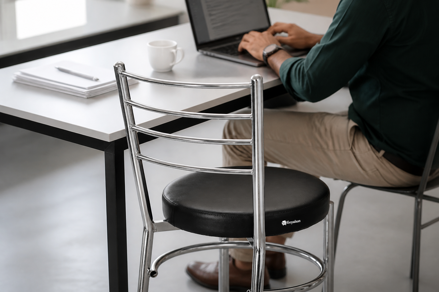 Black chair pulled up to a clean modern office desk with a laptop, coffee mug, and minimalist workspace setup.