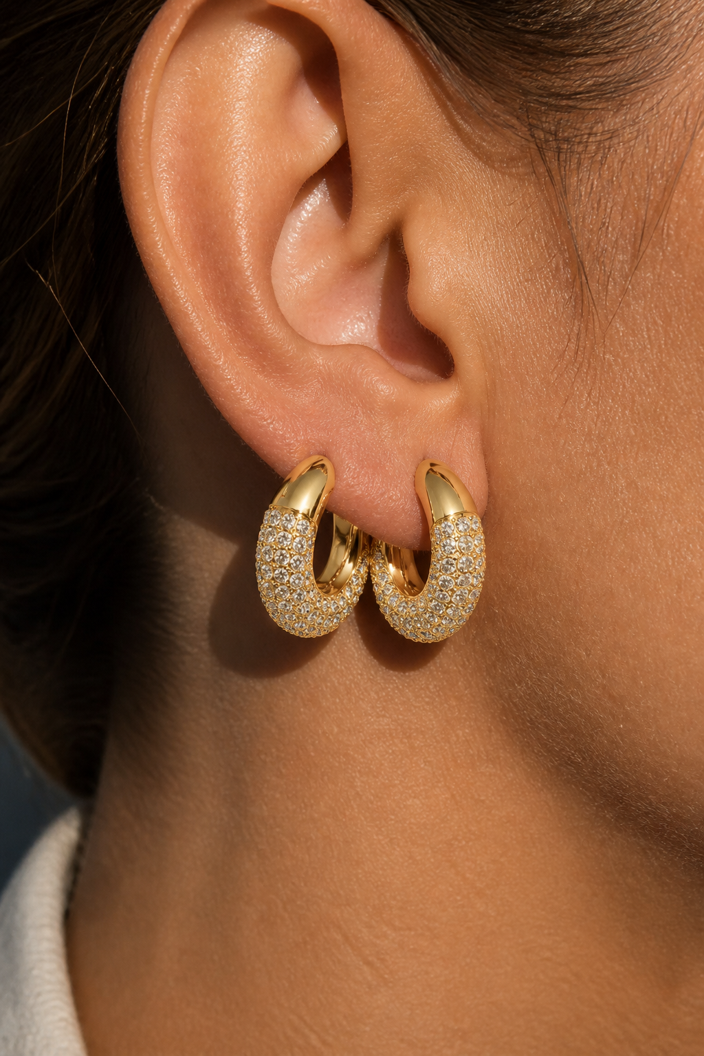 Macro close-up photograph of pavé-set white foiled crystals on the Dextera hoop showing every facet catching light on warm skin tone