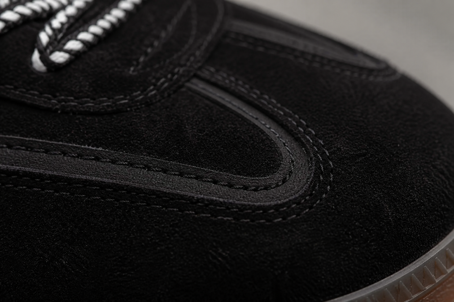 Macro close-up of deep black suede texture on Aeres NOIR sneaker showing the light-absorbing nap and quality grain