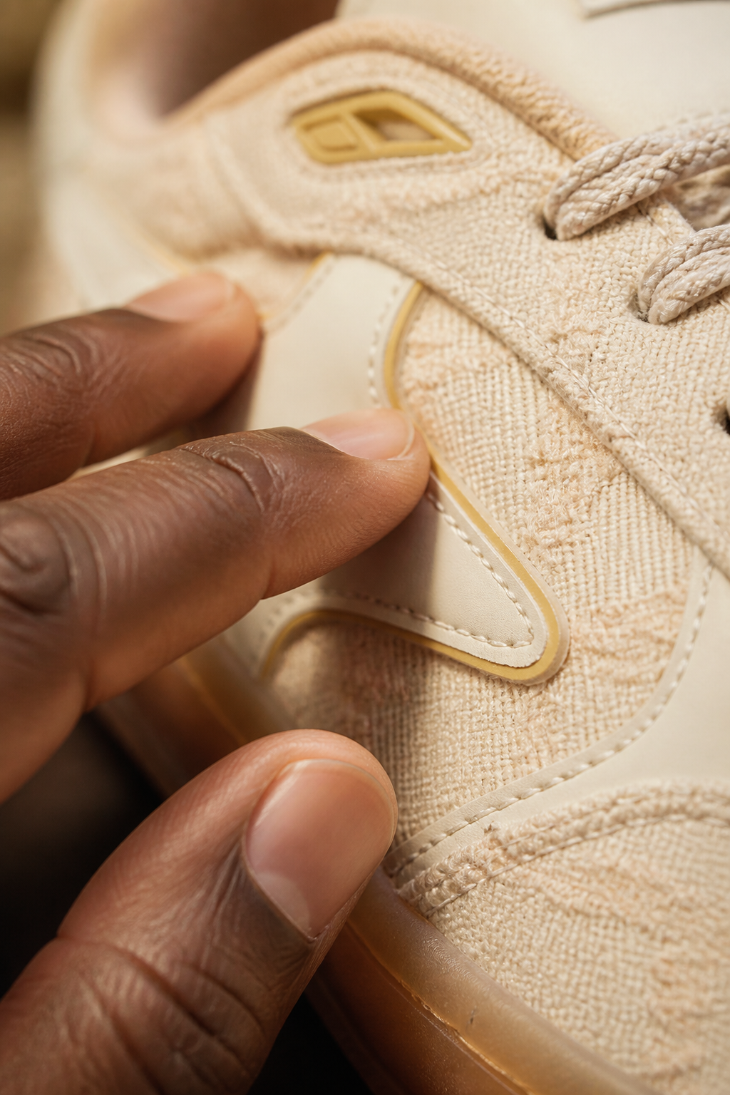 Close-up of premium textured cream synthetic fabric with soft hand touching to show exceptional softness and quality of Aeres HALO upper material
