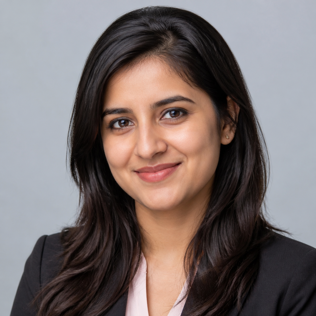 Friendly smiling Indian woman in her thirties with shoulder-length dark hair, soft natural window light, neutral blurred indoor background, warm approachable headshot portrait