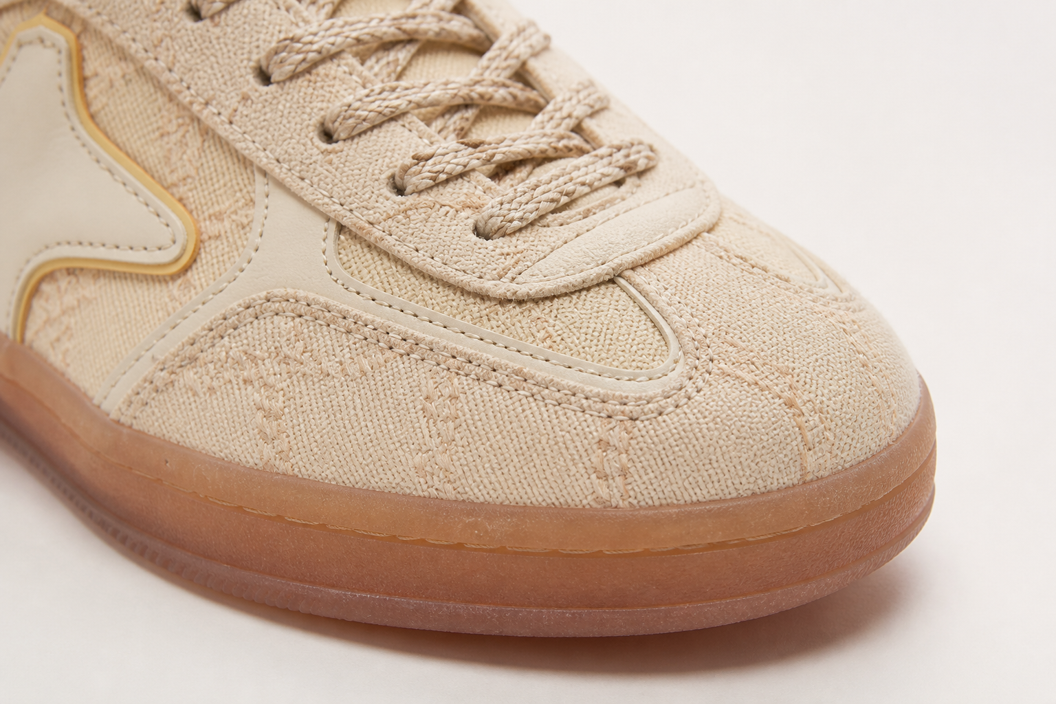 Close-up macro shot of Aeres HALO vintage-style T-toe panel construction showing precise stitching and premium textured cream synthetic fabric with soft natural lighting