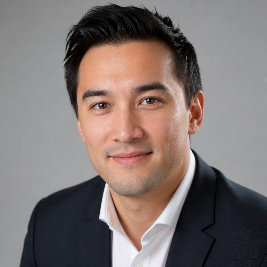Friendly headshot of an East Asian man in his early forties with short dark hair, soft daylight, blurred modern kitchen behind him, calm confident smile