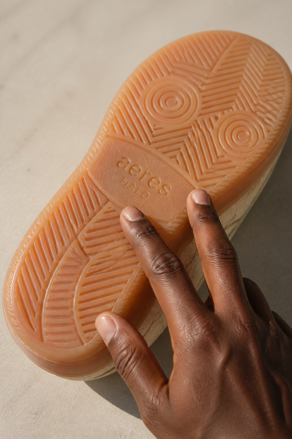 Macro photography of Aeres HALO 100% pure rubber sole texture showing detailed grip pattern and durability with hand touching surface to demonstrate quality