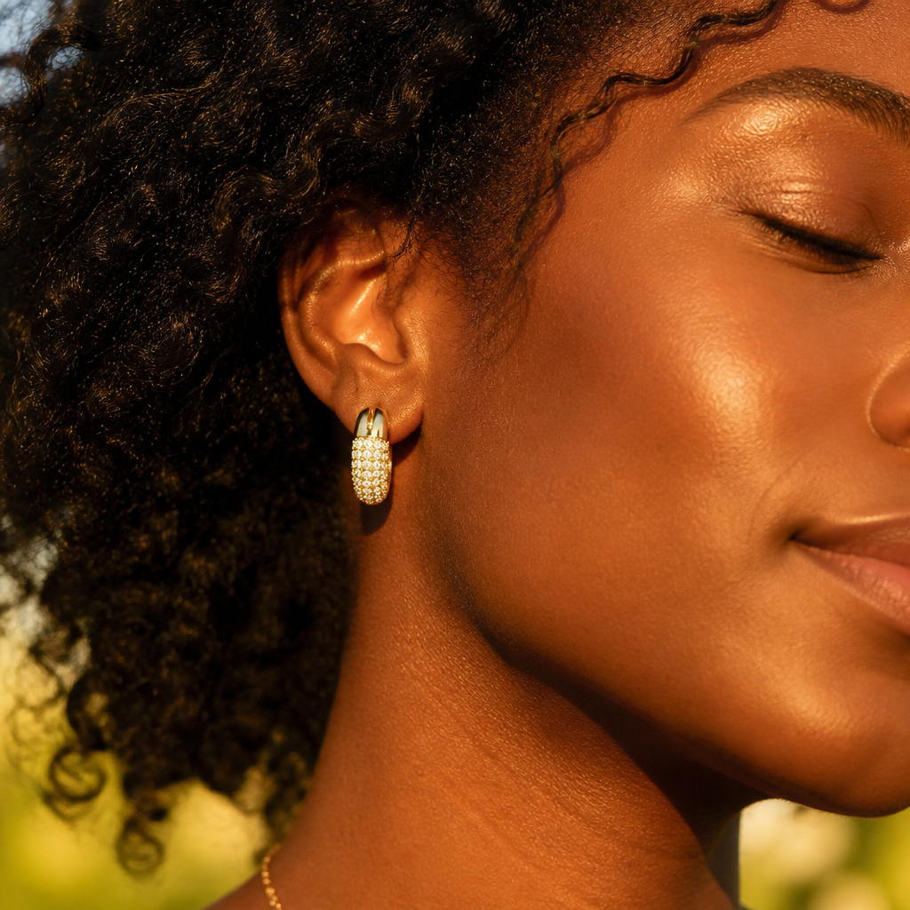 Close-up of a woman wearing the Dextera Small hoops in warm golden sunlight, pav&eacute; crystals catching light like tiny stars on her ears