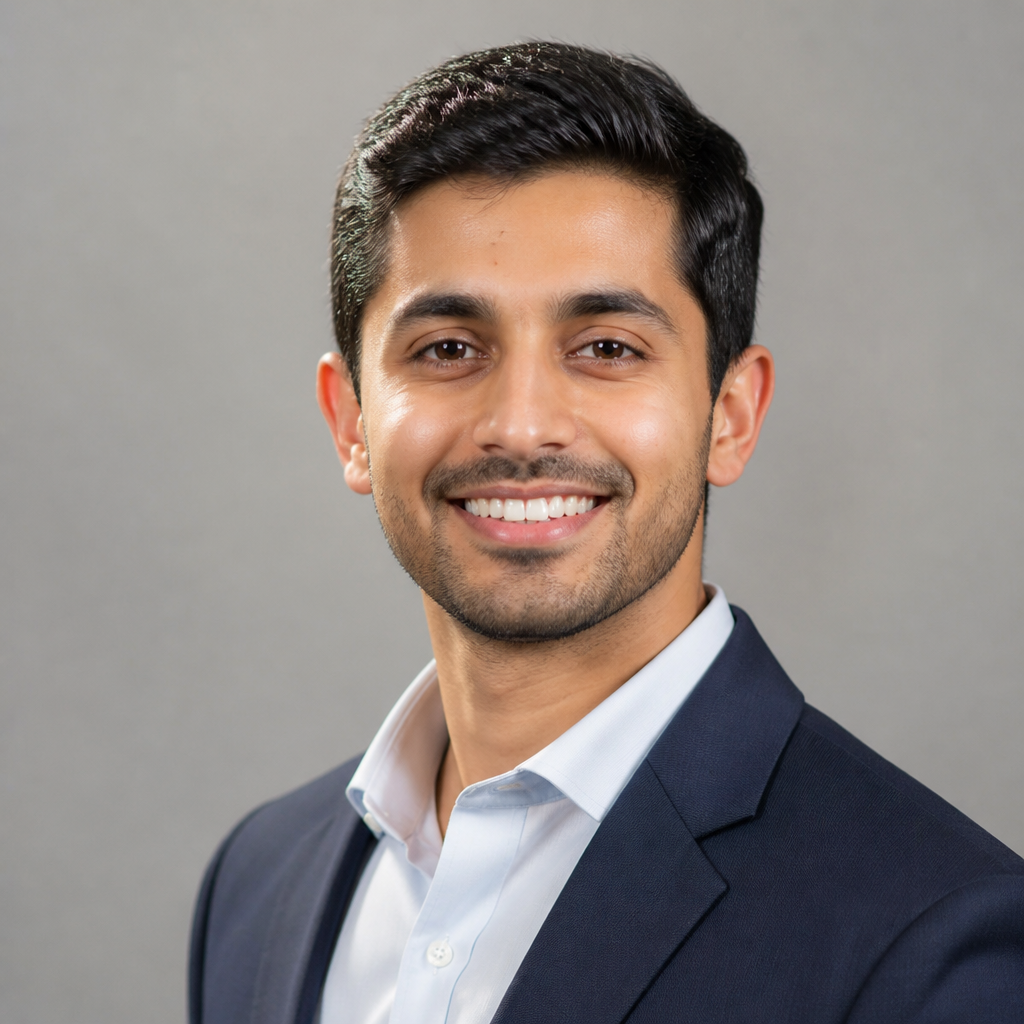 Warm candid portrait of a smiling young Indian man with short dark hair wearing a casual white t-shirt, soft natural daylight, gentle approachable expression