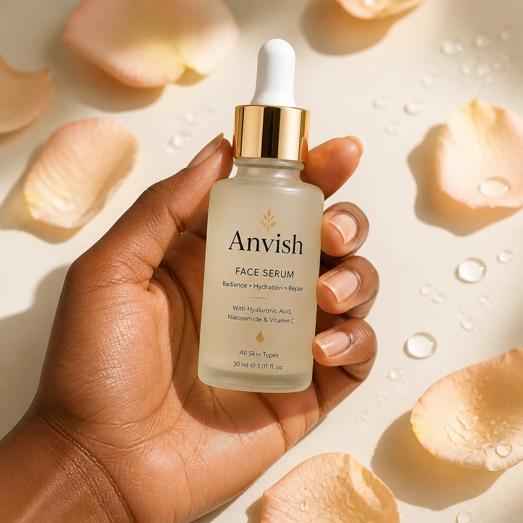 A gentle hand cradling the elegant Anvish Face Serum bottle surrounded by soft peach petals and clear water droplets on a clean cream background