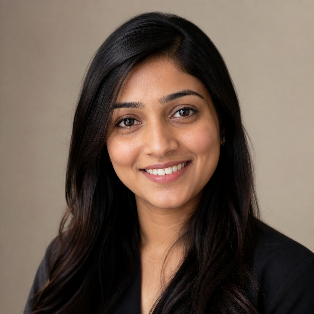 Portrait of Priya Sharma, a young Indian woman with long dark hair, smiling softly against a blurred Bengaluru co-working space with warm indoor lighting