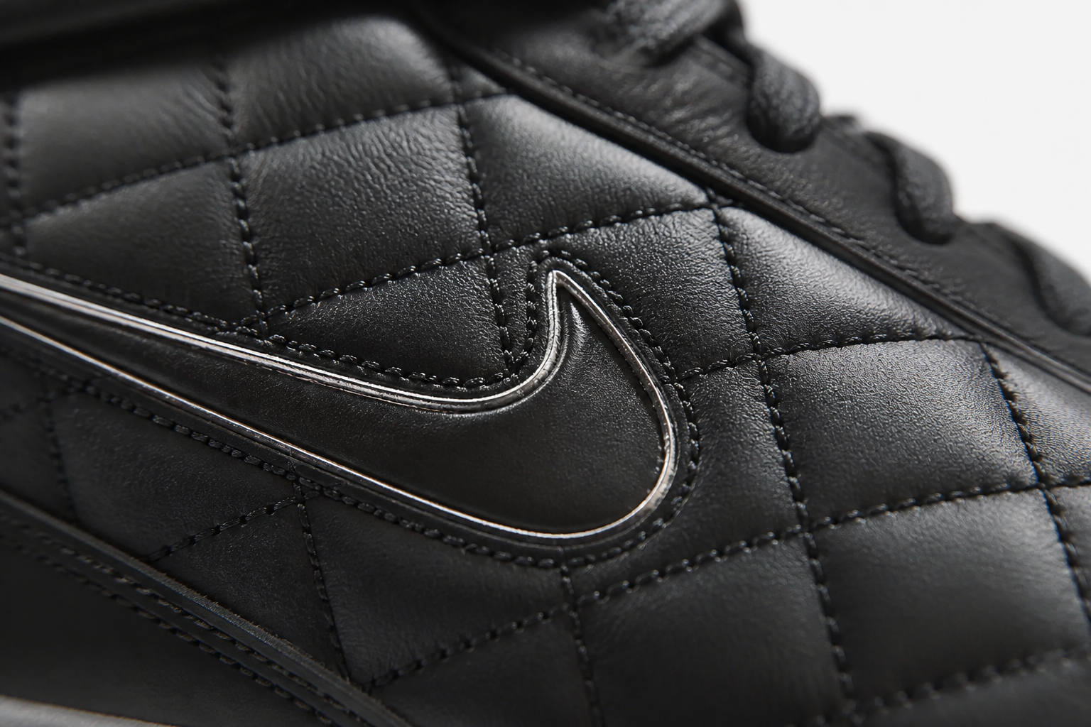 Extreme close-up detail shot of Nike Total 90 Premium quilted upper texture showing intricate stitching patterns and premium leather finish under soft studio lighting