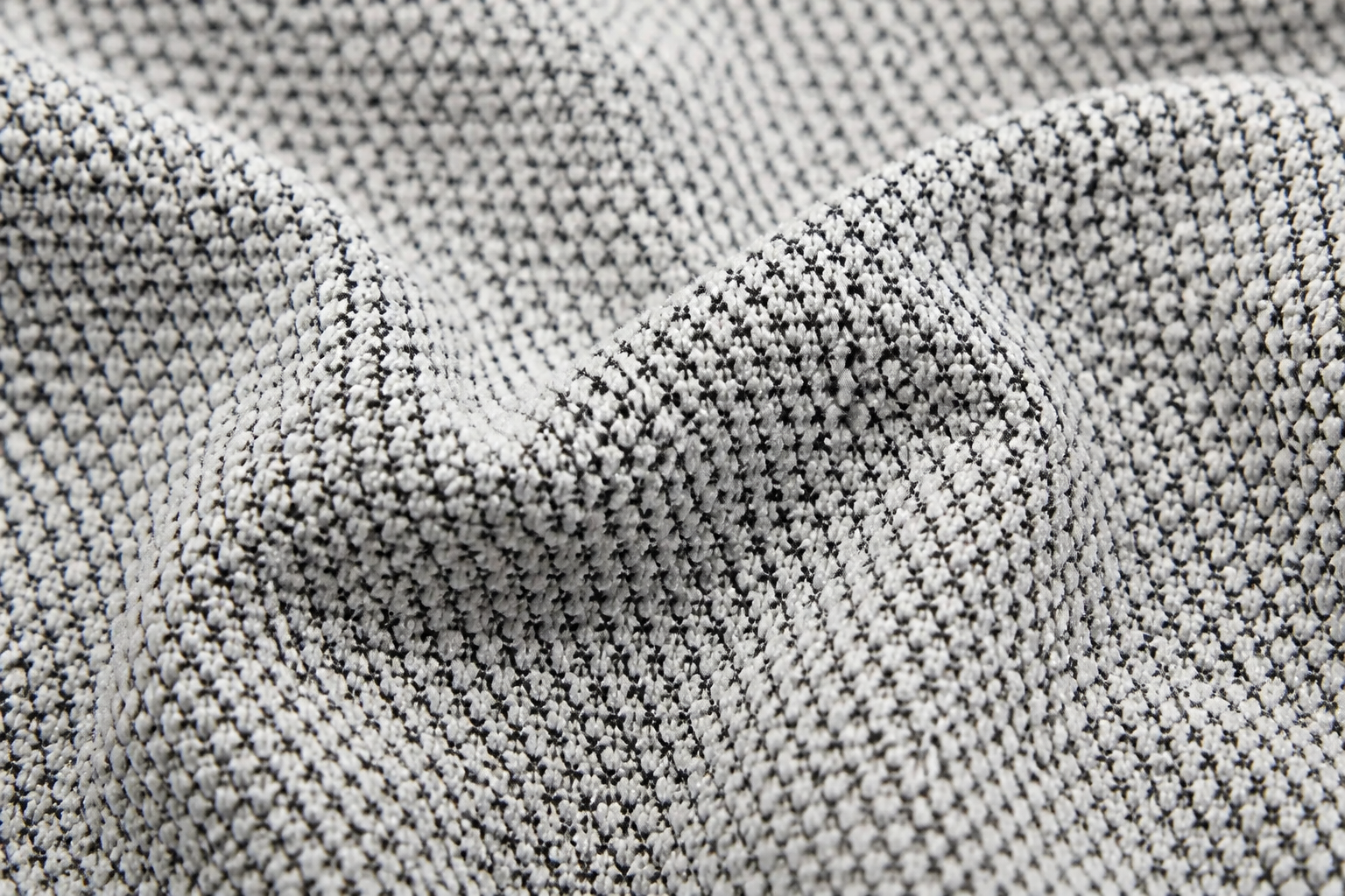 Macro shot of soft cotton fabric weave texture in soft natural light showing premium flat-knit quality