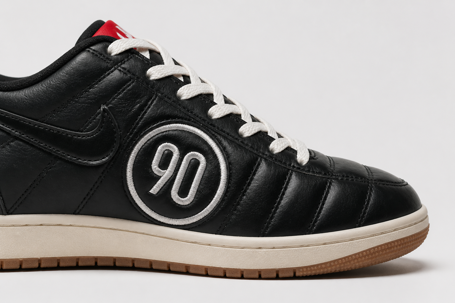 Side profile close-up of the Nike Total 90 Premium showcasing the bold embroidered Total 90 logo stitched onto the heel and tongue with crisp white thread on a deep black leather upper