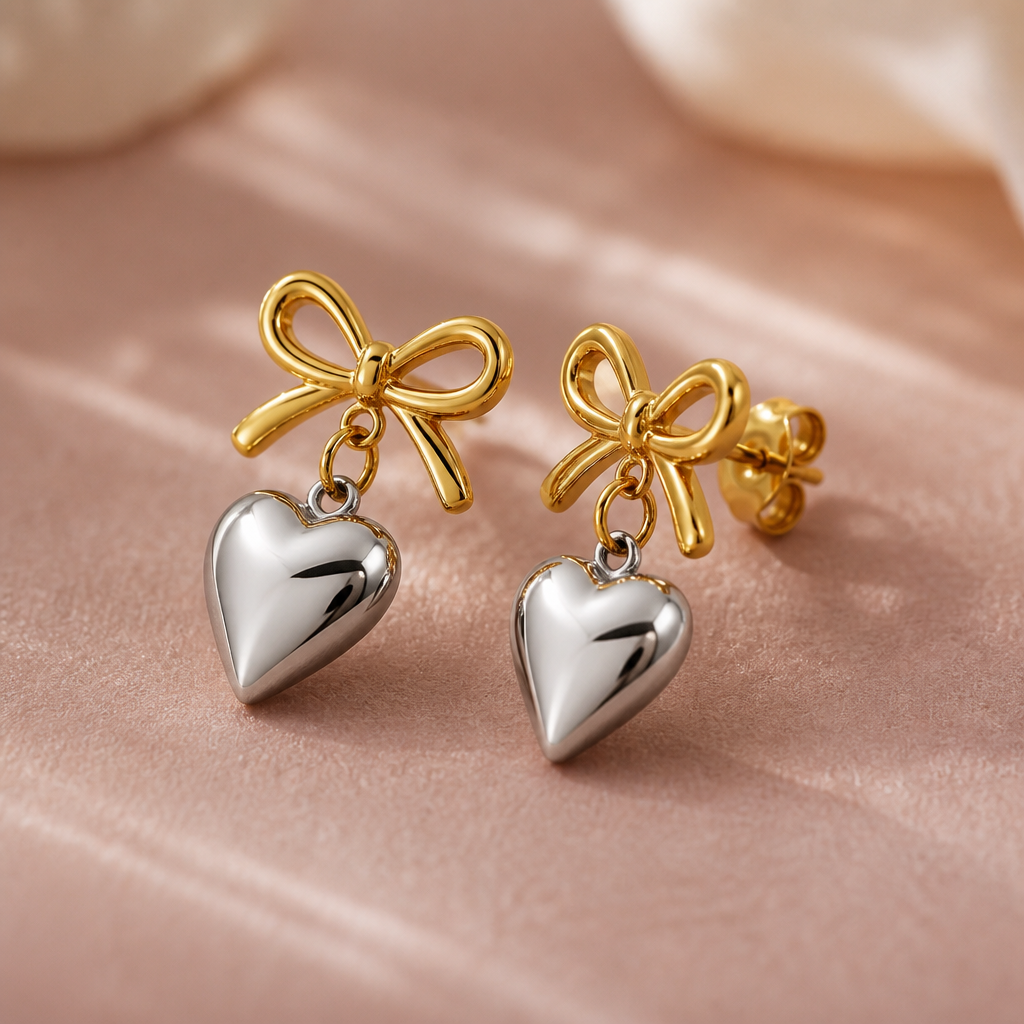 Macro product photograph of the Love Heart Earrings wrapped knot showing polished gold and silver details against a blush background