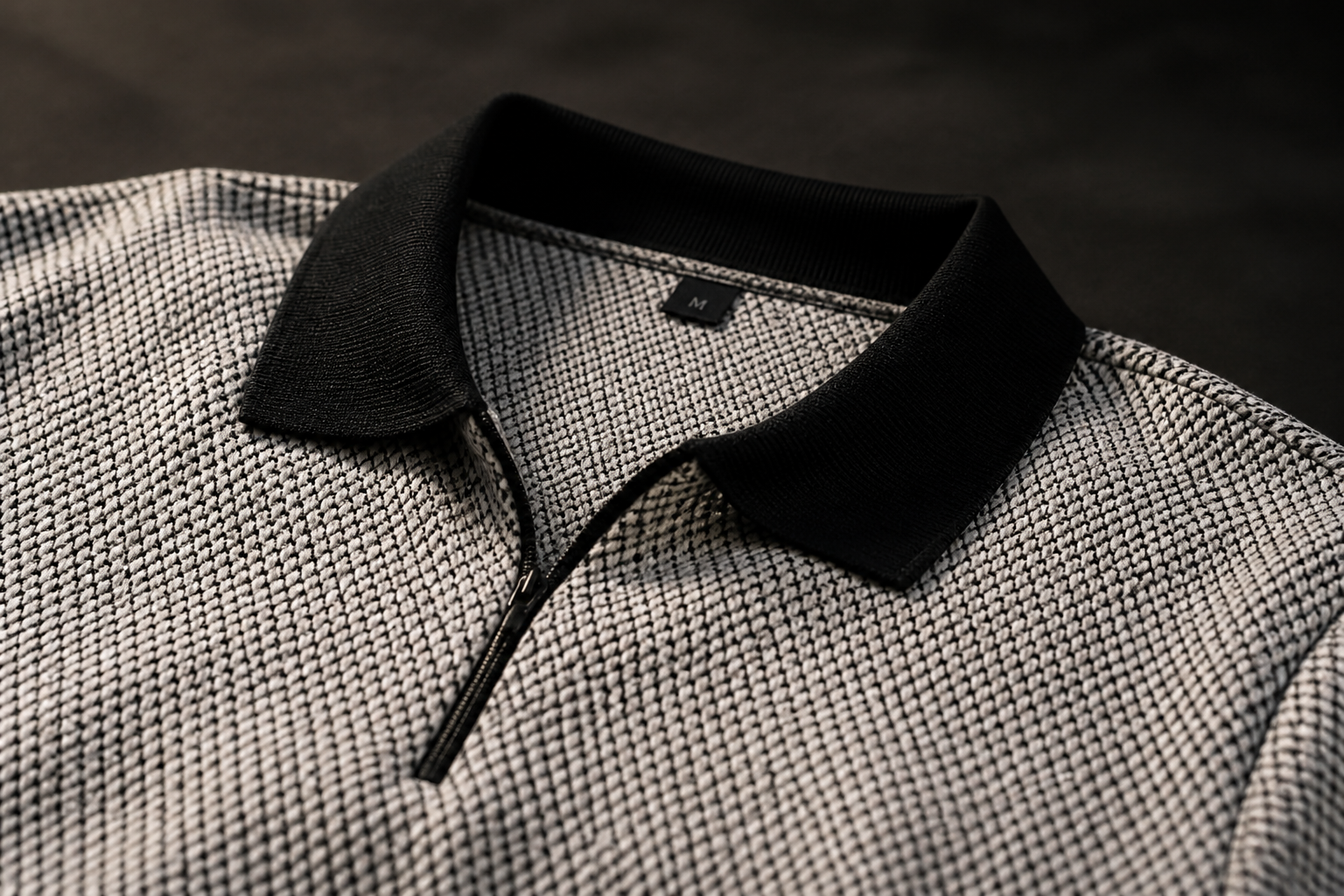 Macro detail of the premium cotton knit texture and fine stitching of the Posh Monk polo against a moody dark backdrop, luxurious mood
