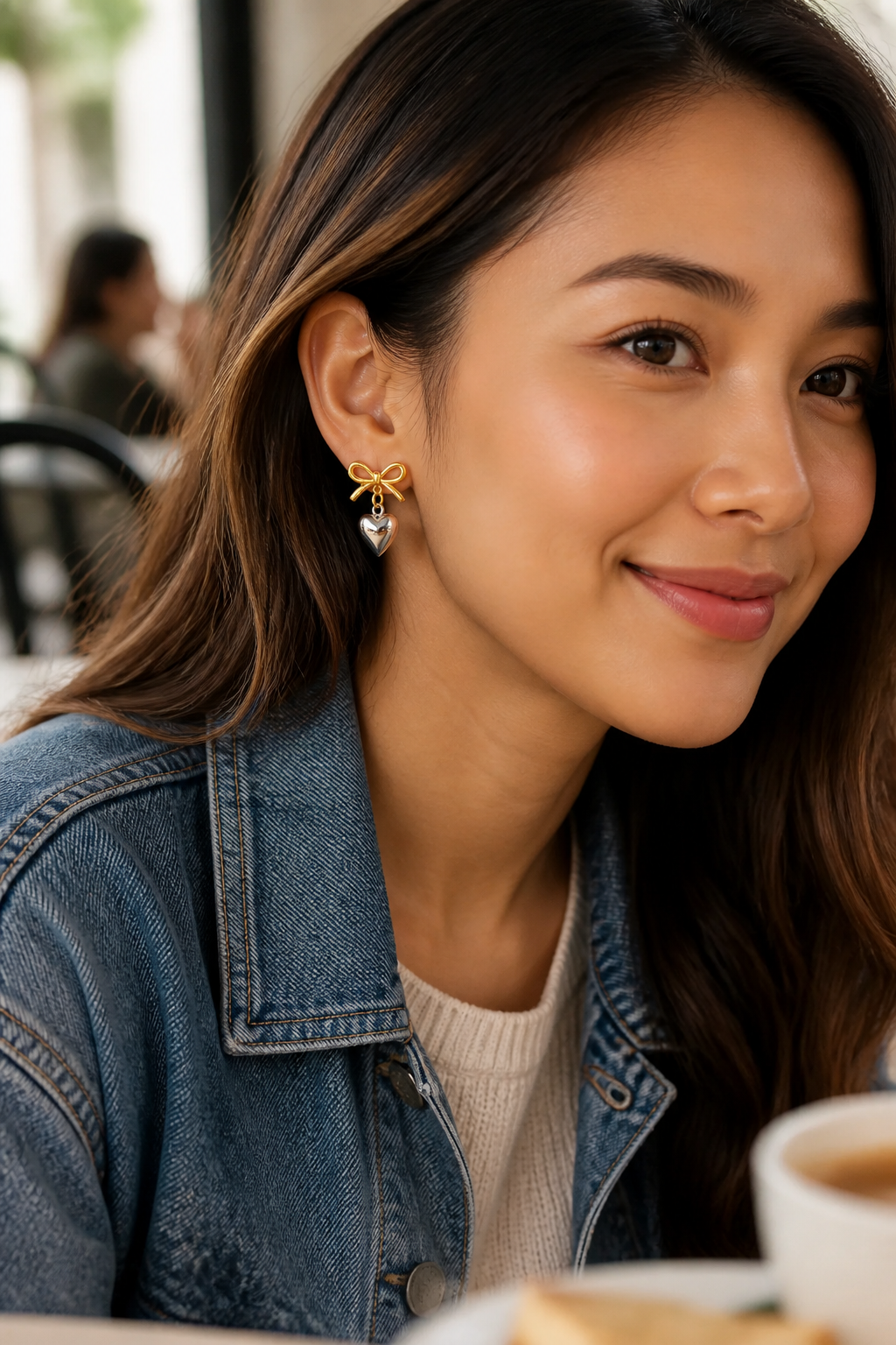 Southeast Asian woman smiling at a weekend brunch while wearing delicate heart earrings in warm natural light
