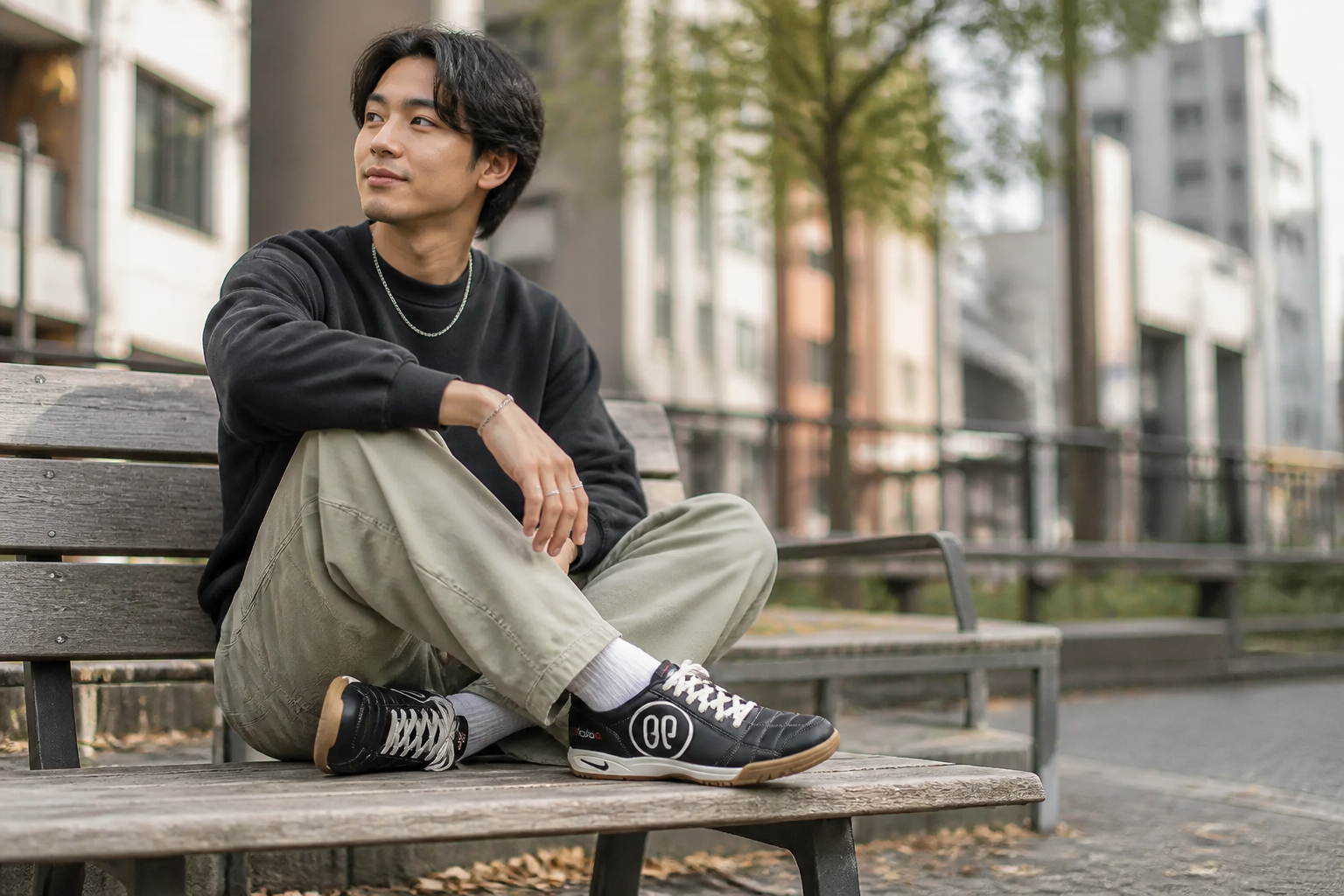 Person sitting cross-legged on a city bench wearing lightweight Nike sneakers with relaxed posture showing all-day comfort