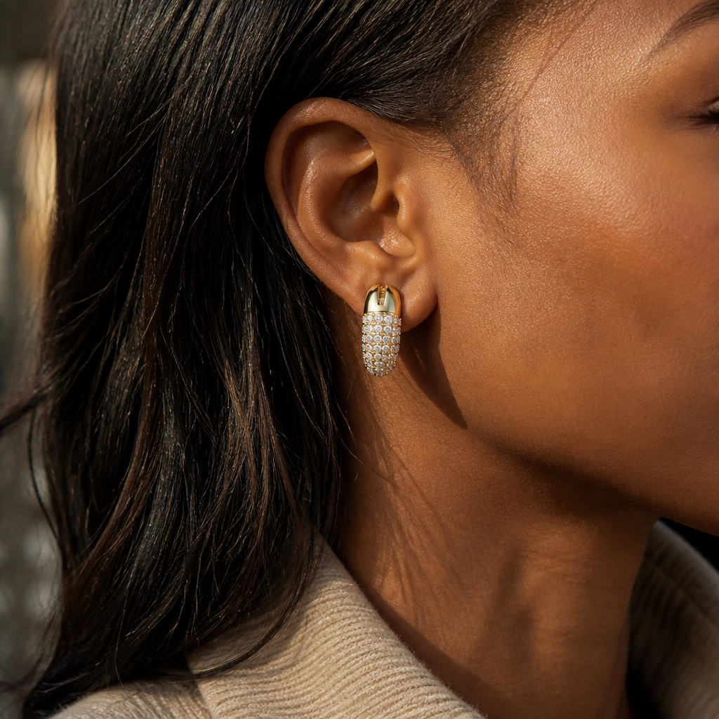 Close-up product thumbnail of Dextera Small gold hoop earrings resting in a dark luxury presentation tray, faceted crystals softly catching warm studio light