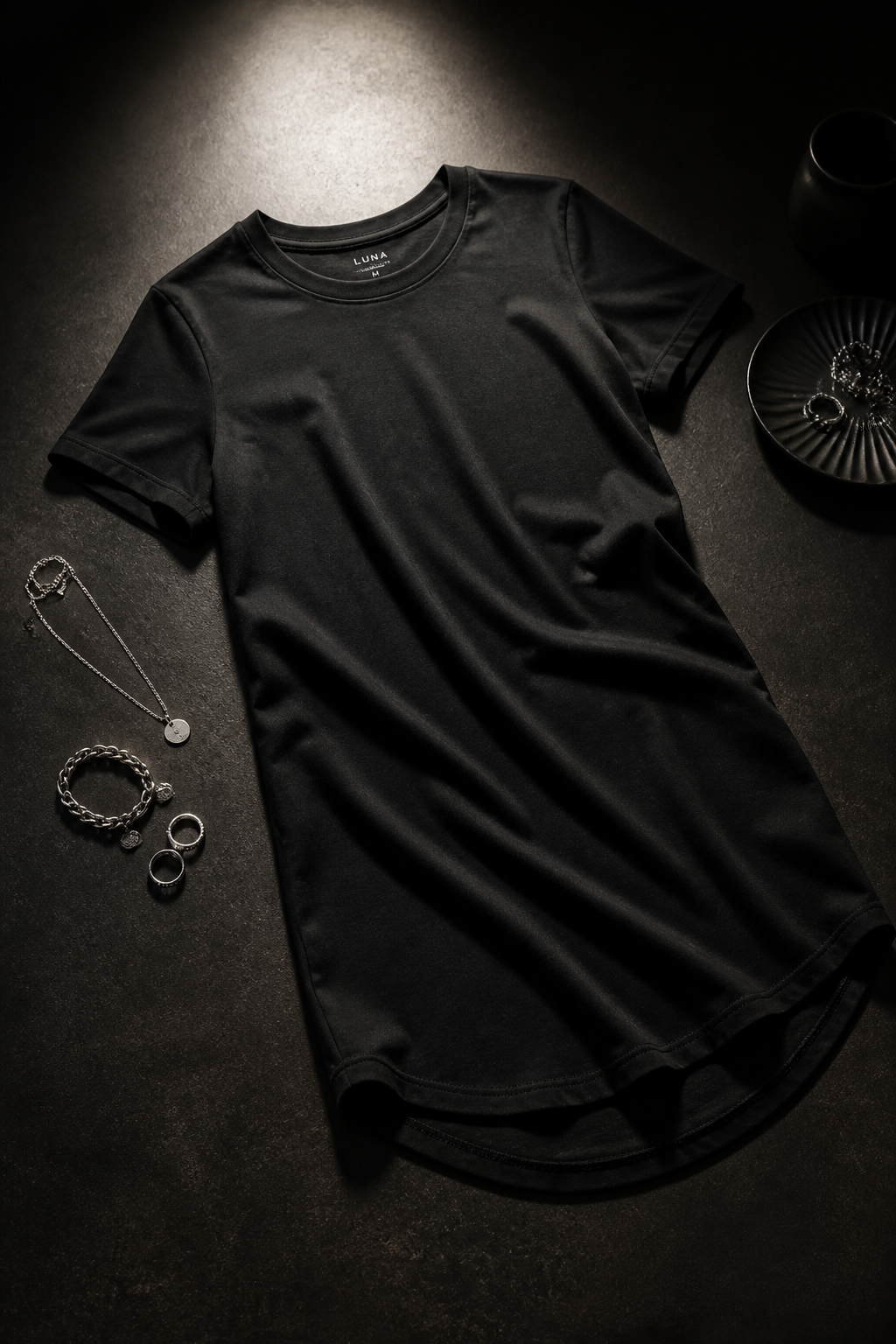 Black Ladies T-Shirt in Long length Cotton fabric styled with silver accessories on dark moody background with single spotlight illumination