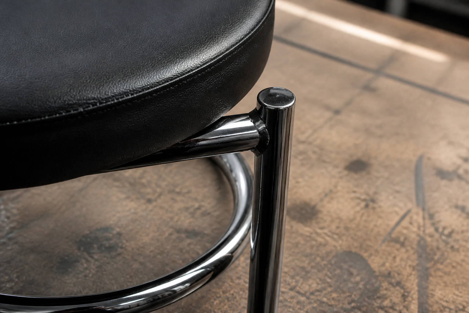 Macro detail shot of the heavy-duty steel frame and welded corner joint of the Goyal chair showing strong steel tubing, clean welds, and powder-coated black finish on a workshop bench.